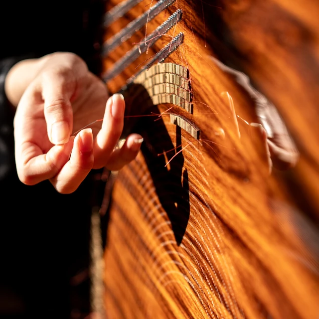 A person embroidering beads into a rosewood panel