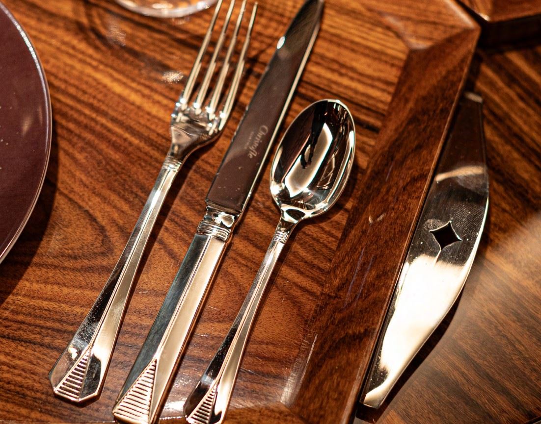 Silverware laid on top of a luxuriant wood table.