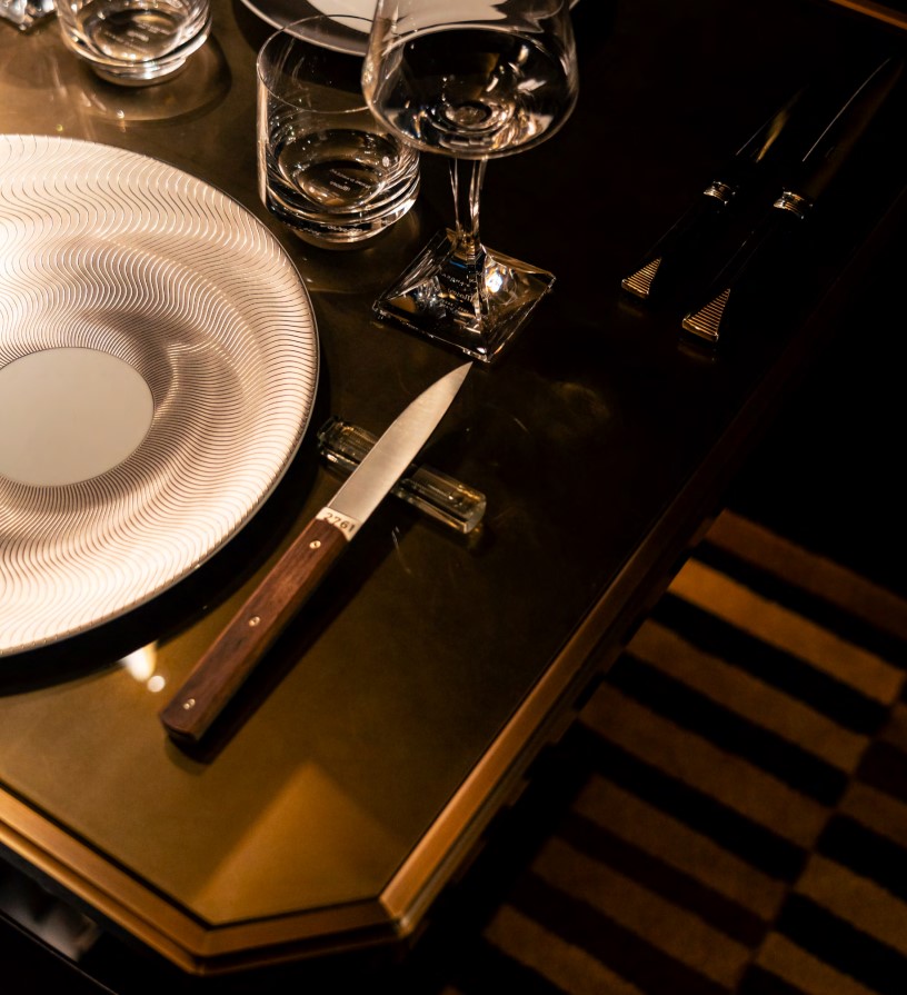 A dinner knife set on a table next to a plate and drinking glasses.