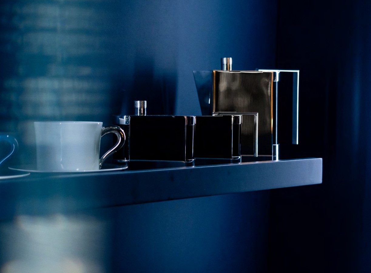 Geometric metal teapot and tea set in cool-colour lighting.