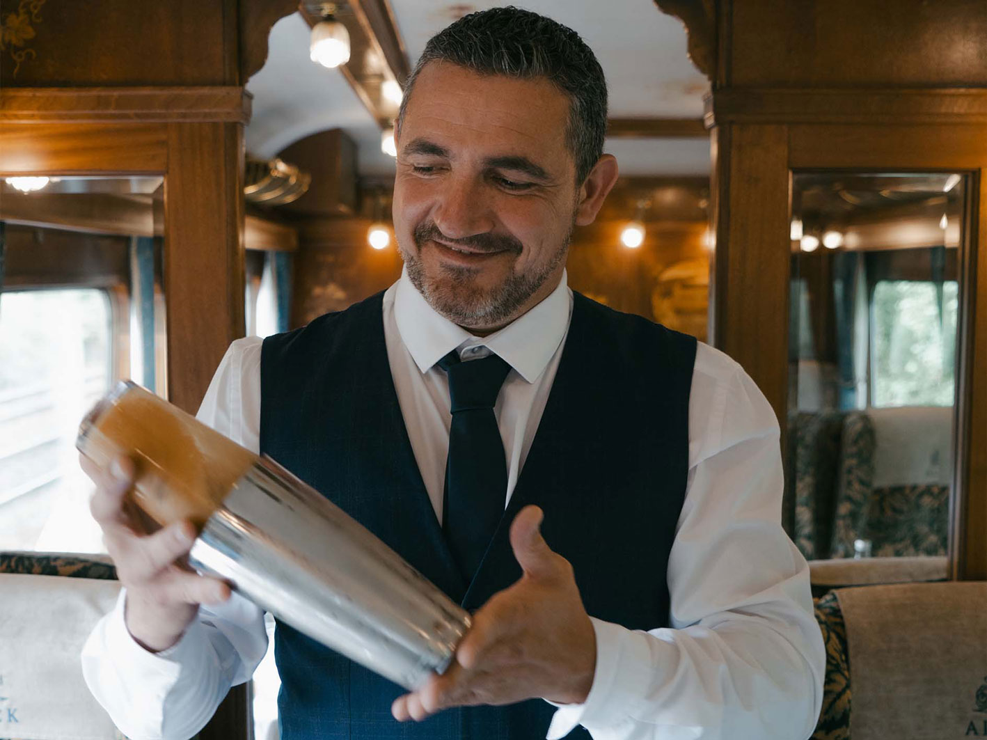 A man bartending, shaking a mixer.