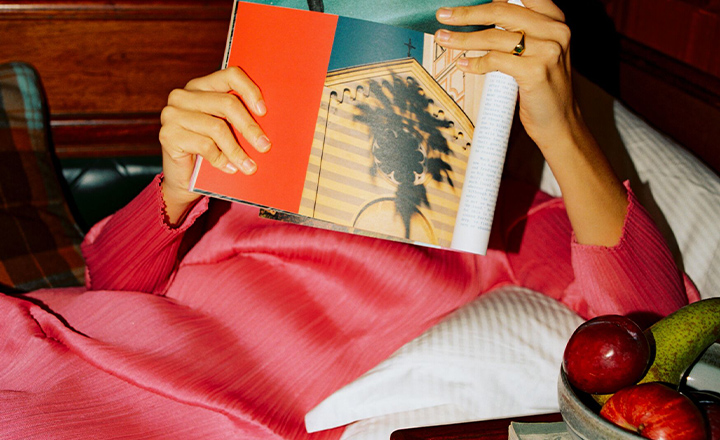 A lady in a chic red dress, lounging with a magazine.