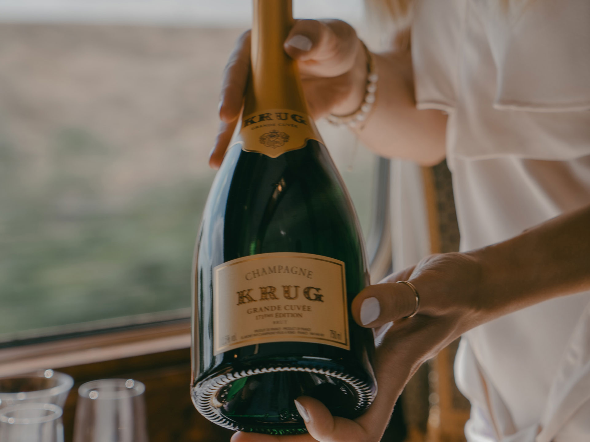 A pair of hand presenting a bottle of champagne