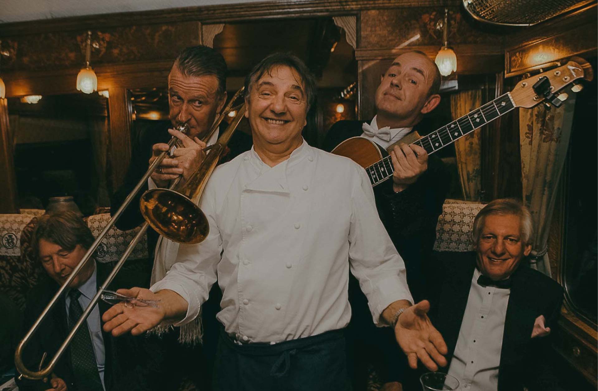 Two people playing instruments and a man smiling at the camera.