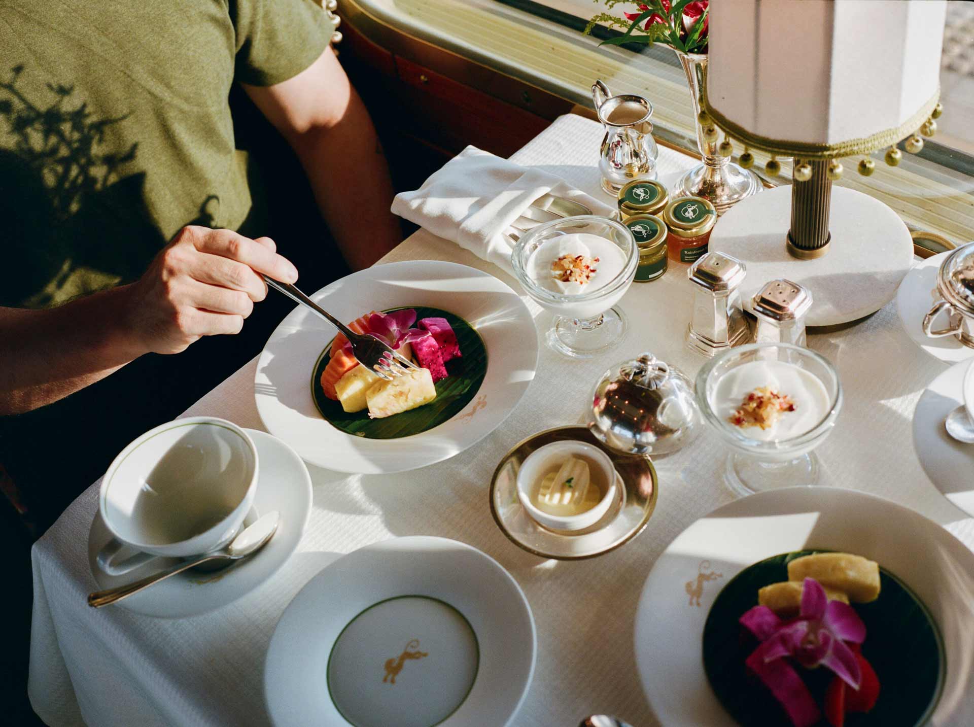 A person holding a fork and eating a plate of vibrant fruit.