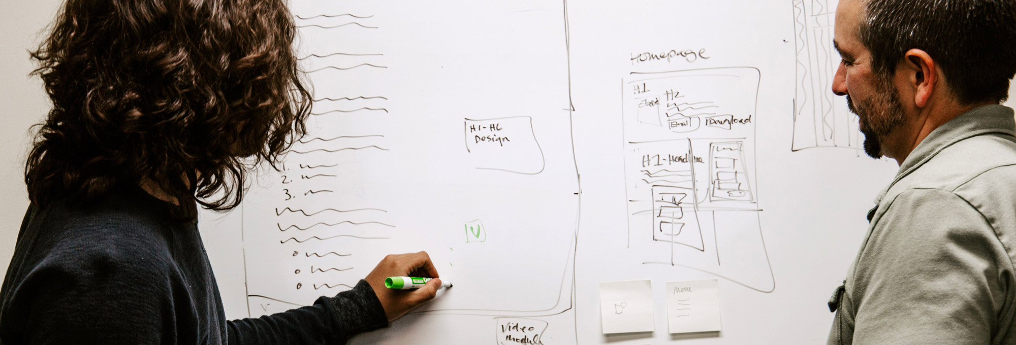 man wearing gray polo shirt beside dry-erase board