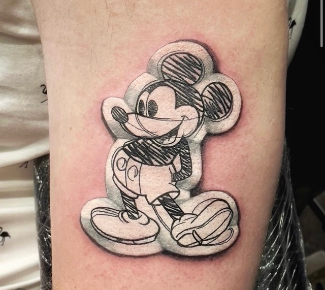 Tattoo of a stylized, sketch-like Mickey Mouse with shading and bold outlines on a person's skin.