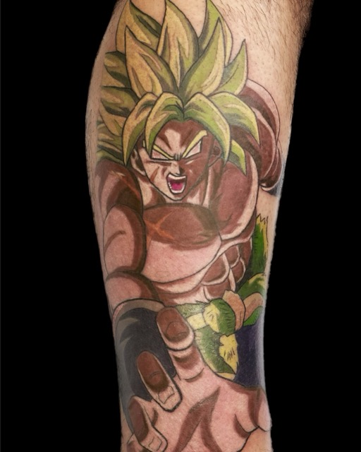 Tattoo on forearm of a muscular anime character with spiky green hair, wearing a fur belt, shown in an aggressive pose with one arm extended forward.