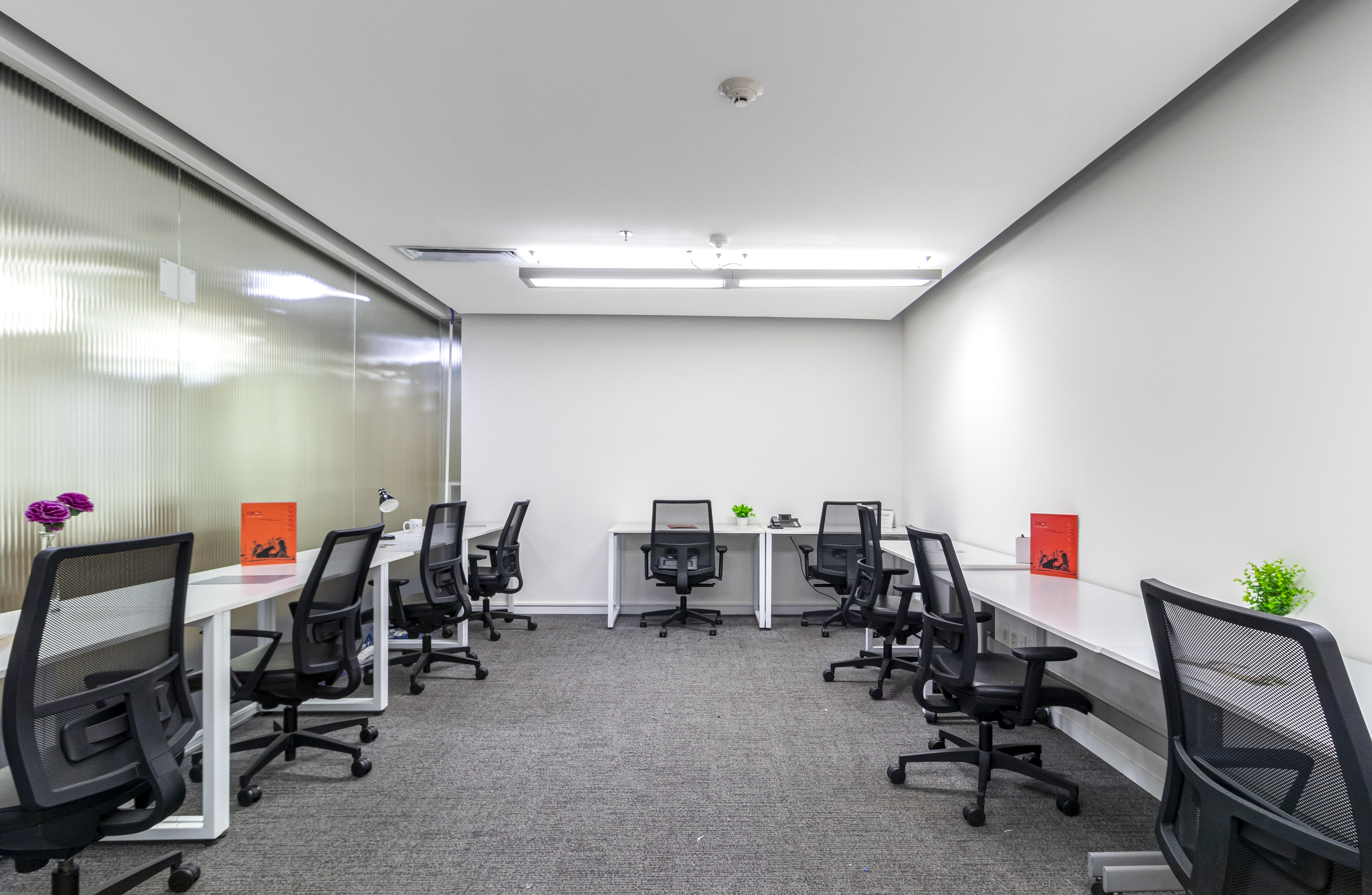 Oficina amueblada con escritorios y sillas gerenciales con buena iluminación 