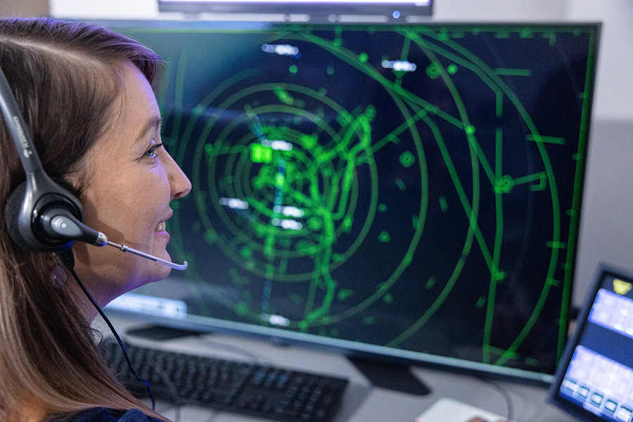 Woman wearing headset training on Adacel's MaxSim for Radar Simulator for Air Traffic Control Training.