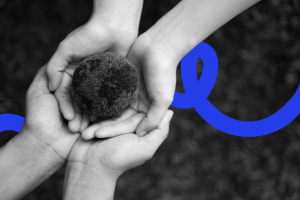 A parent and childs hands holding a mini globe made of moss.