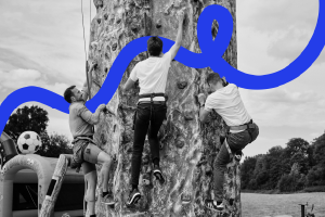 Three people climbing a climbing wall at different stages.