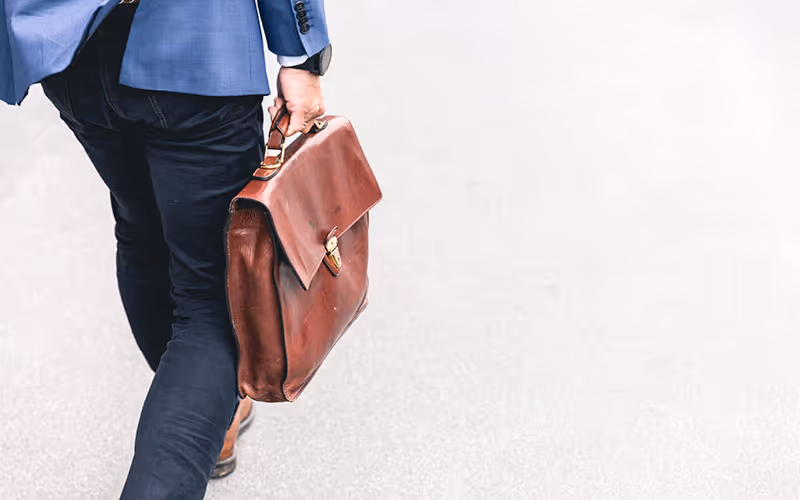 Man walking with brown business bag - Photo by Marten Bjork on Unsplash 