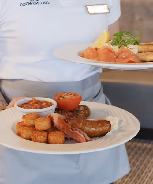Server holding 2 plates of breakfast