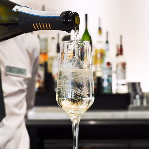 barman pouring wine into a flute