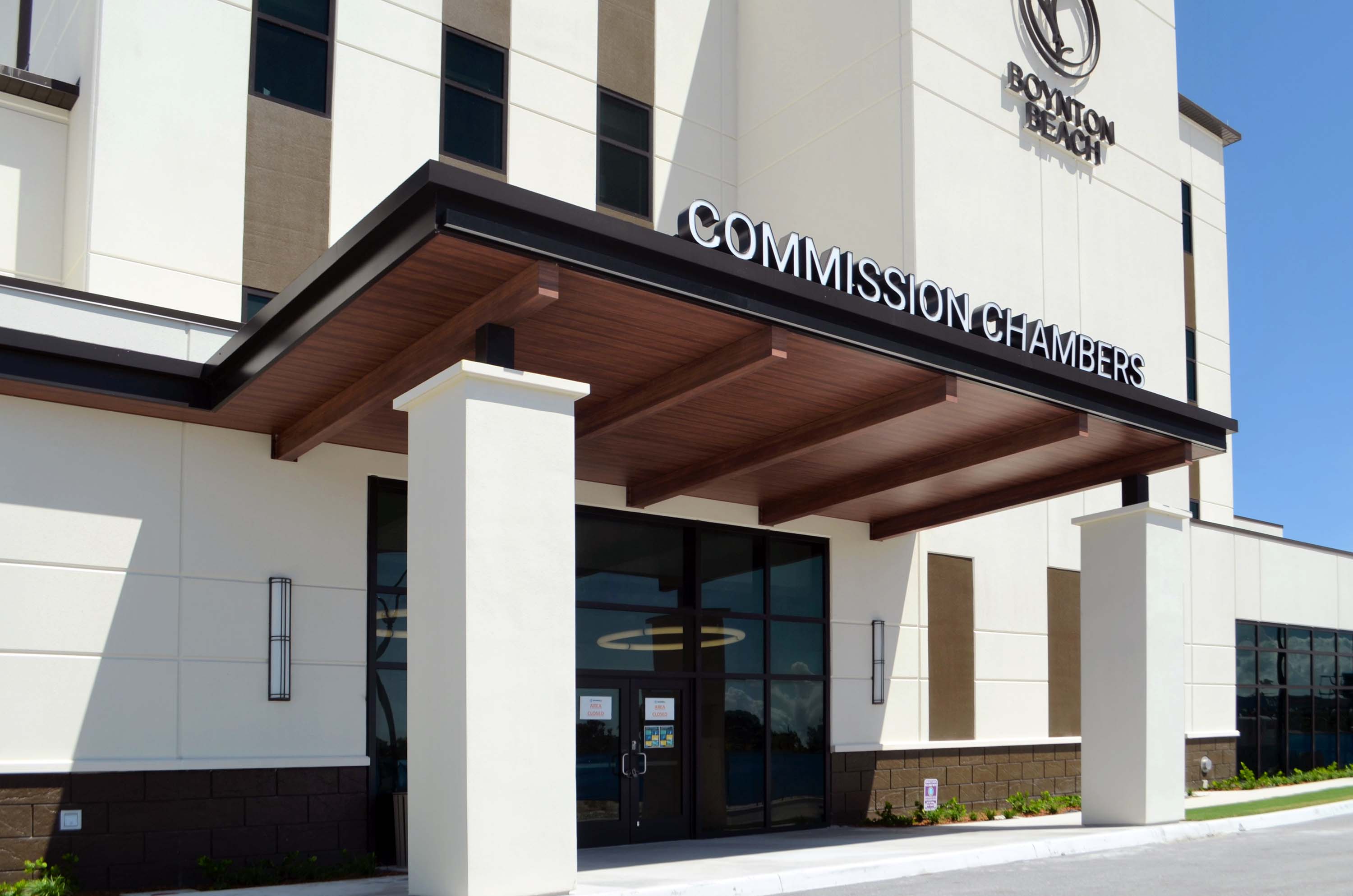 Woodgrain aluminum entry canopy coordinated with building signage, columns, and exterior finishes
