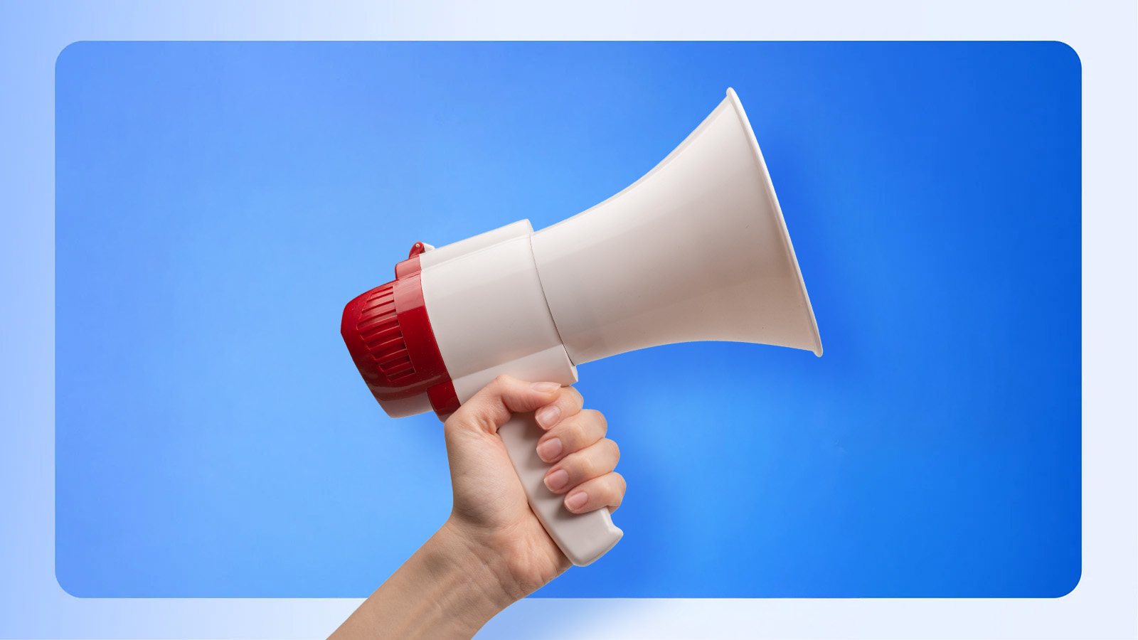 A hand holds up a white and red bullhorn on a blue background