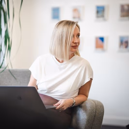 Owner of Epigram, Susan Siddall, sat in an arm chair with a laptop on her knee. Looking to the right of the screen. 