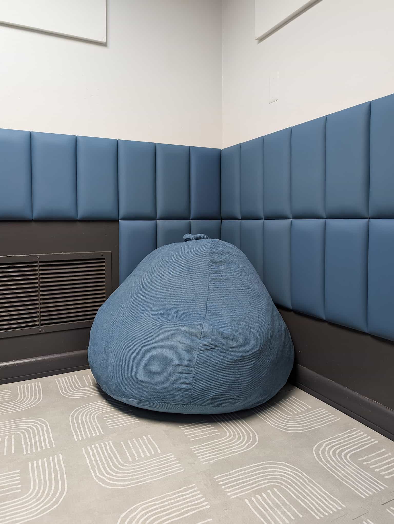A blue bean bag chair surrounded by wall padding