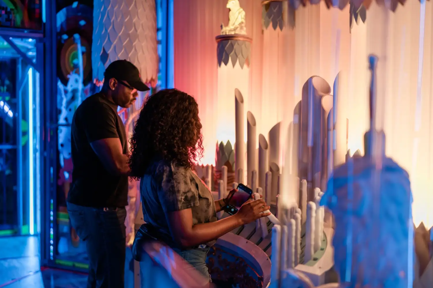 Visitor seated in a neon-lit mech-throne inside a glowing cavern on Eemia, poised before a portal to the stars.