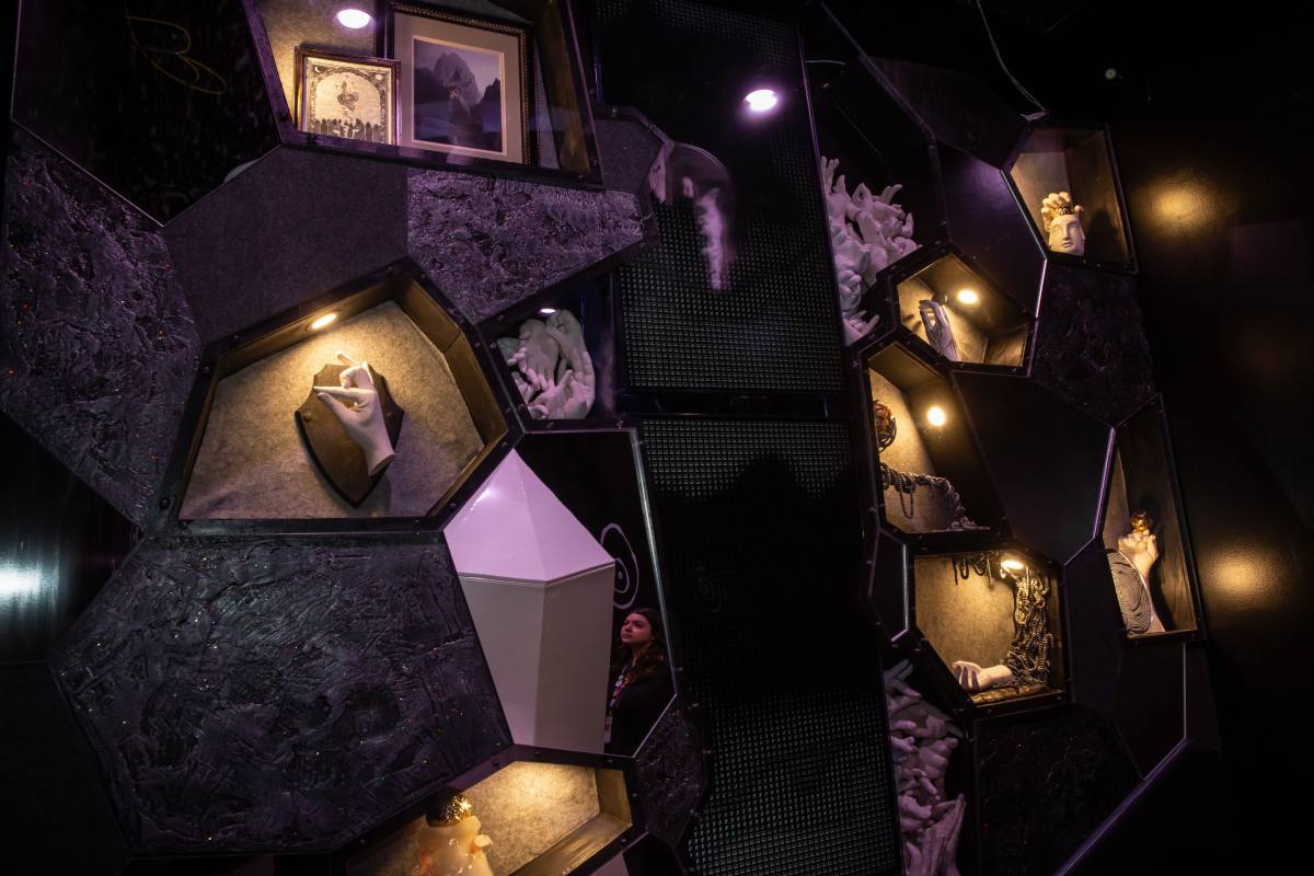 A room with different shaped inlets on the walls holding various gray sculptures, lit with yellow lighting. 
