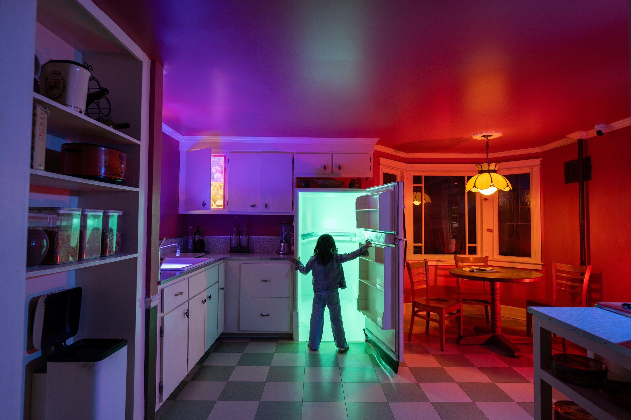 a person standing in a fridge door with red and purple lights