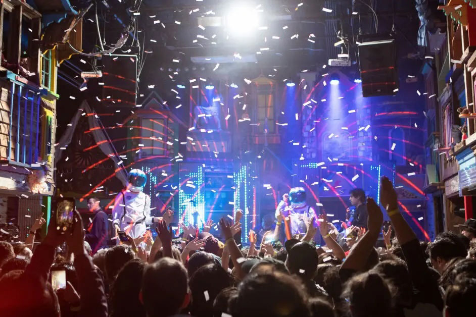 people at a concert dancing with bright lights behind the stage at Meow Wolf
