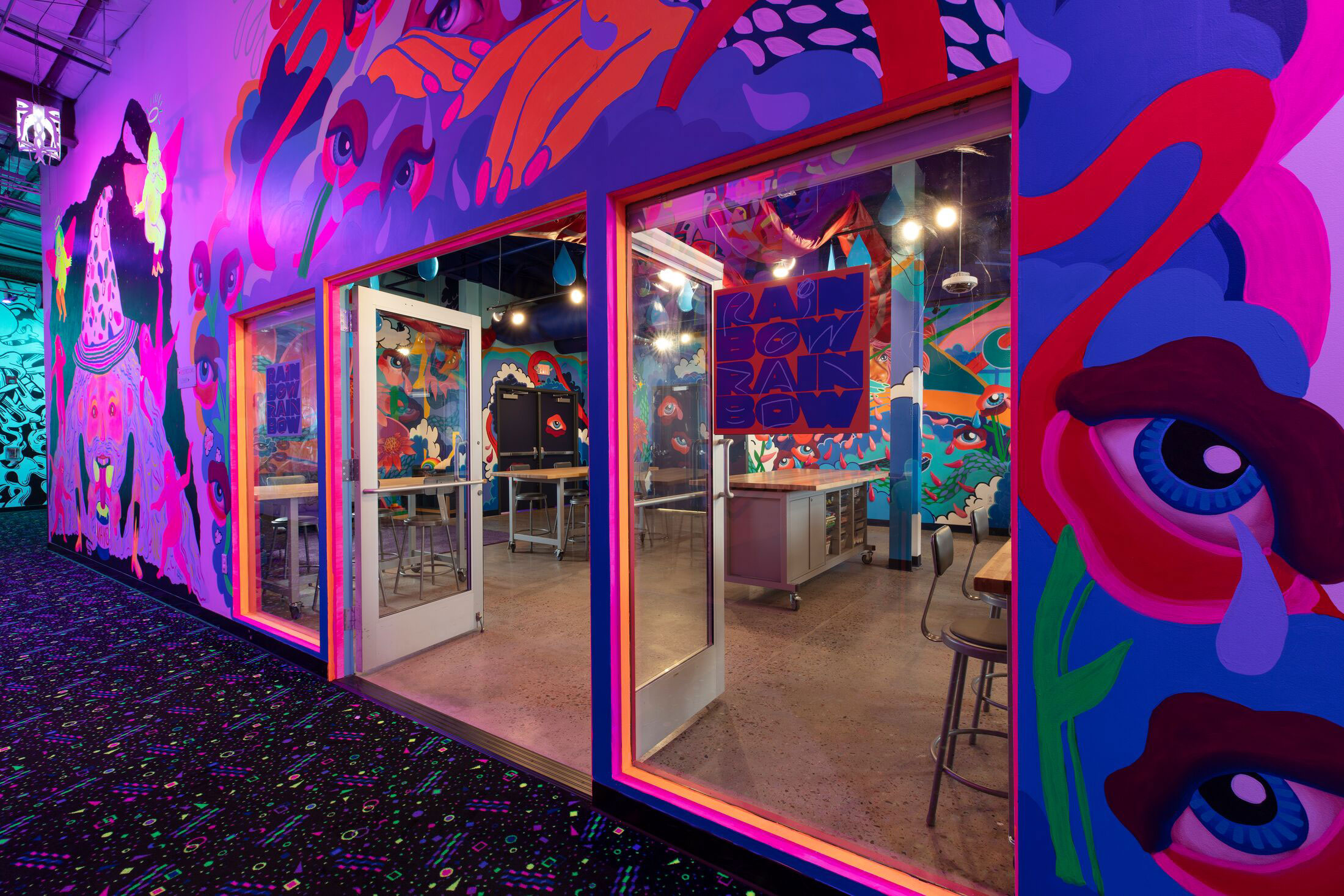 glass doors surrounded by a mural in pinks and purples with giant eyeballs