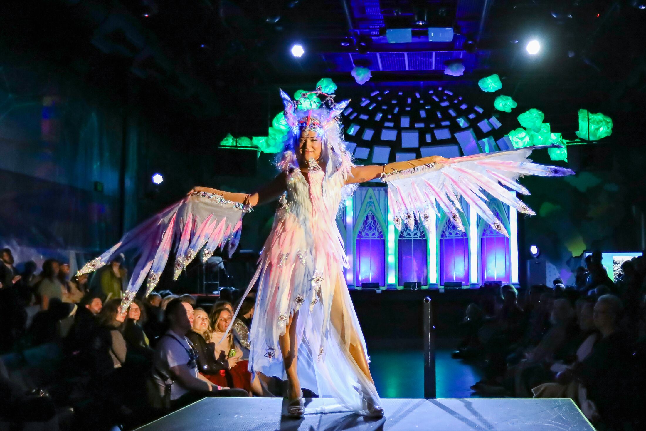 a performance on stage at Meow Wolf Denver against dark blue and green lights