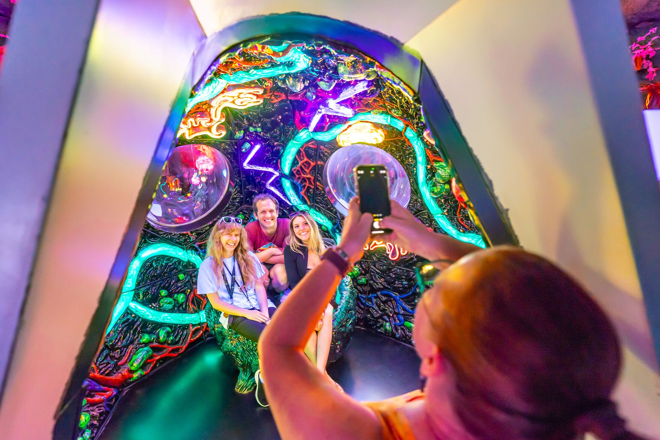 person taking a photo of three people inside a cosmic space