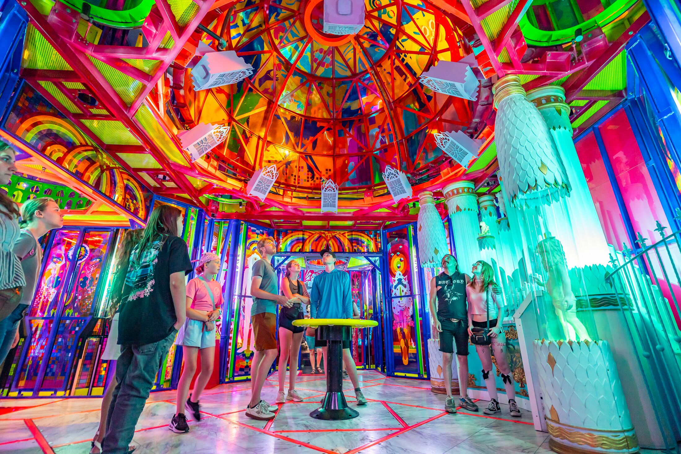 a neon castle with people crowded in the center looking up