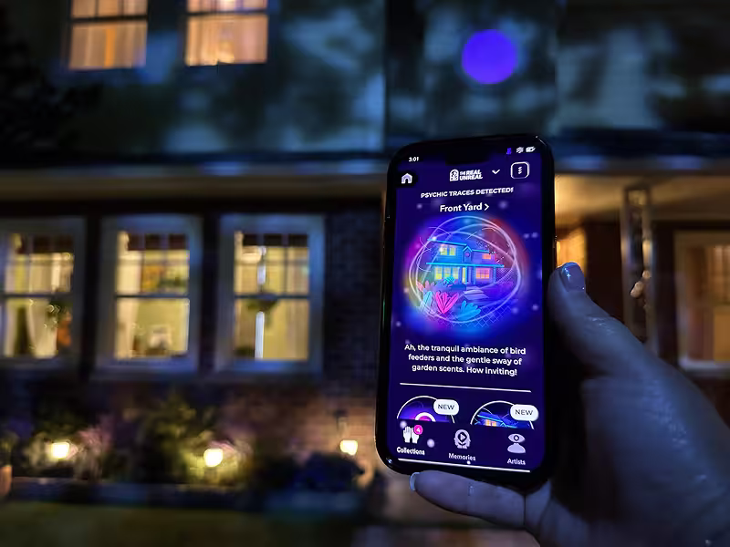 person holding up a phone with the Psychic Sensor on it in front of a house