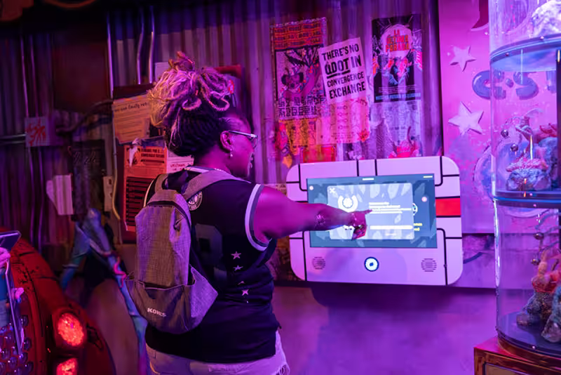person using a QPASS at Meow Wolf Denver to learn more about the story