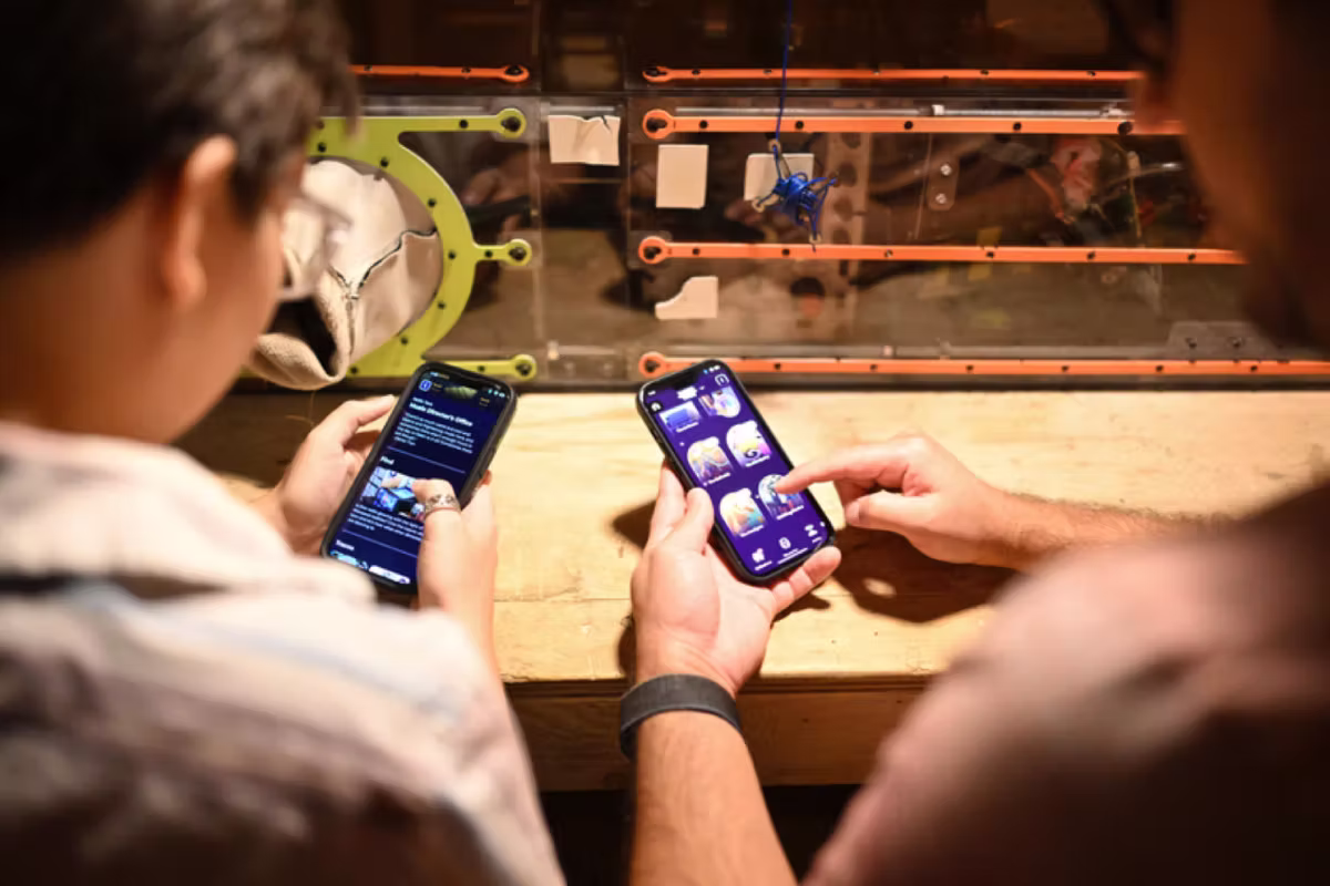 three people surrounding a phone with the Meow Wolf app on it
