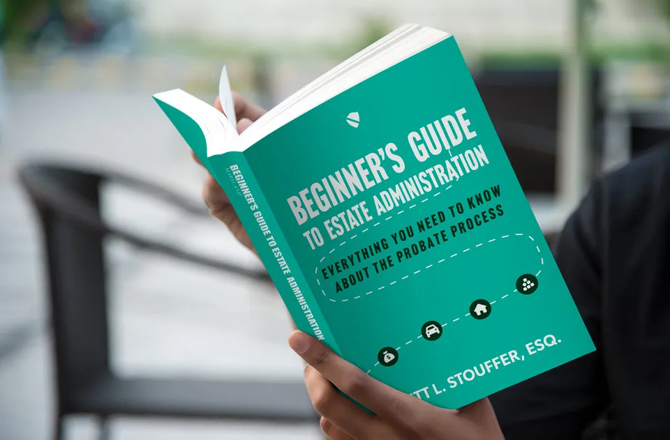 Person holding a book titled: Beginner's Guide to Estate Administration