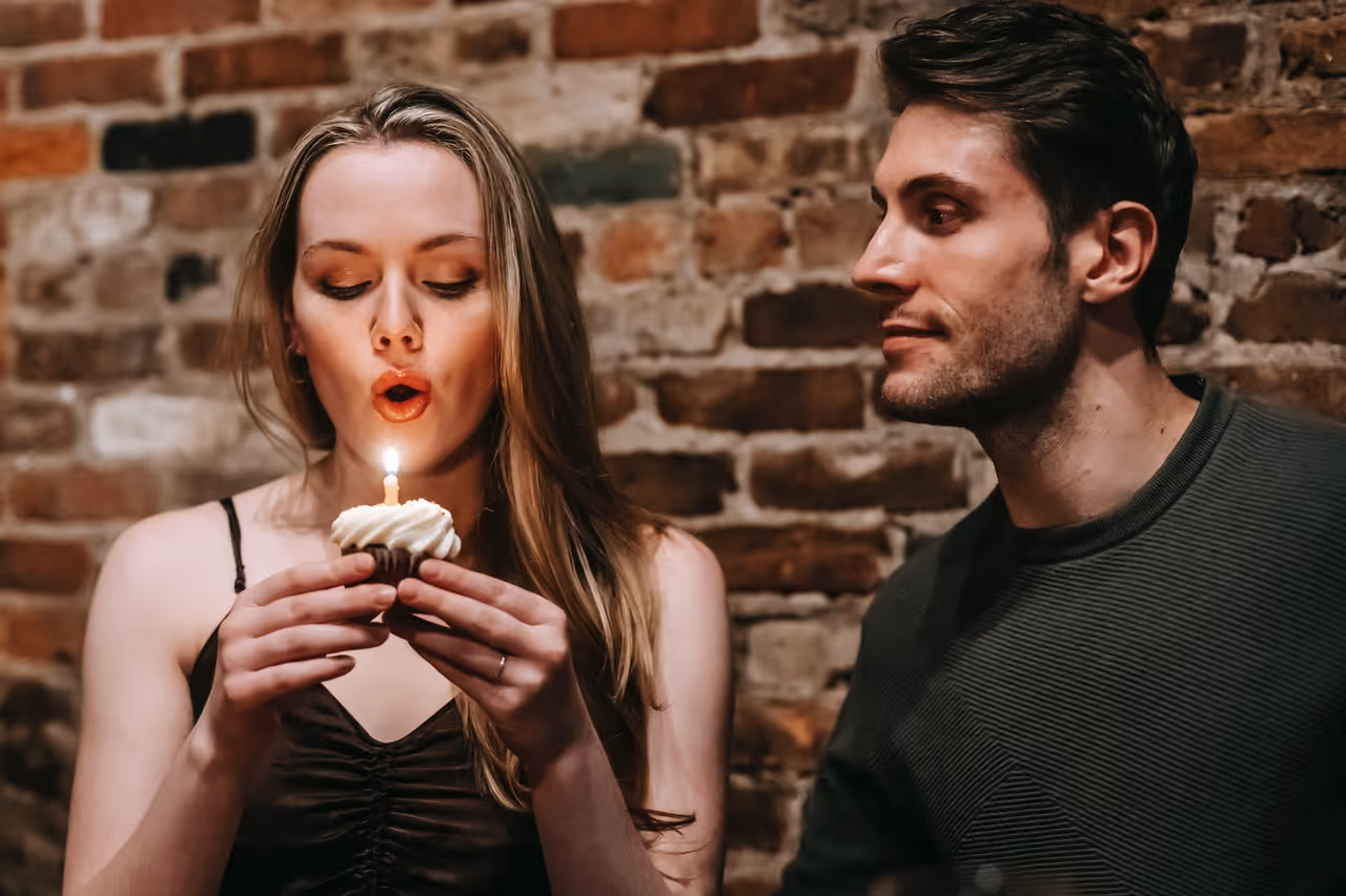 woman blowing out the candle on a cupcake for her 30th birthday