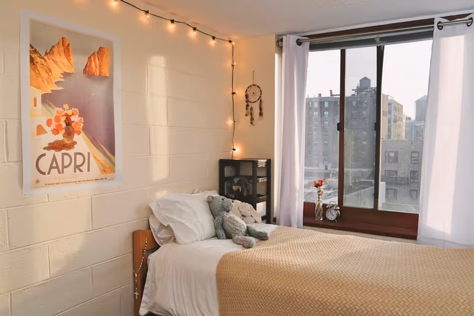 A minimalist dorm room design featuring warm-tinted string lights and a beige color scheme. 