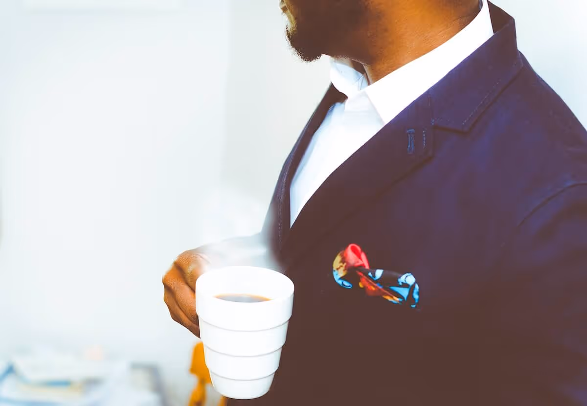 Man in a suit holding a cup of coffee