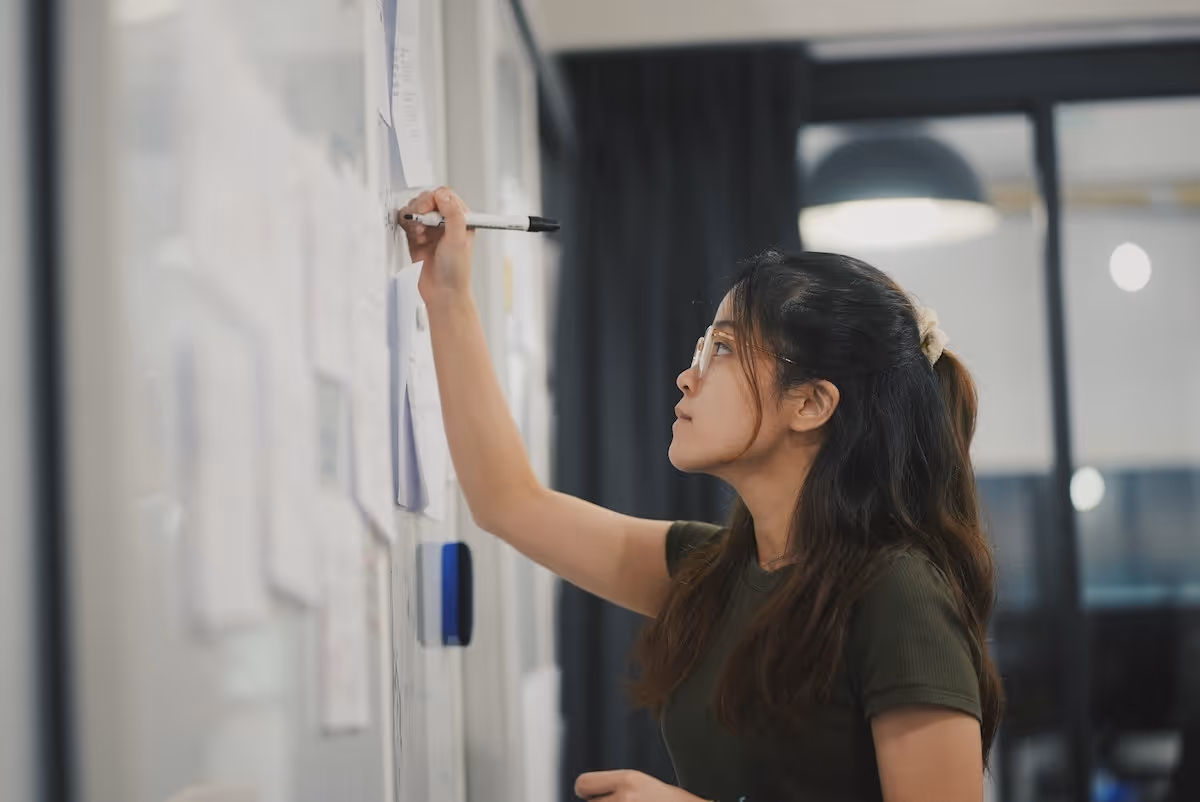 Woman writing on a white board with a marker