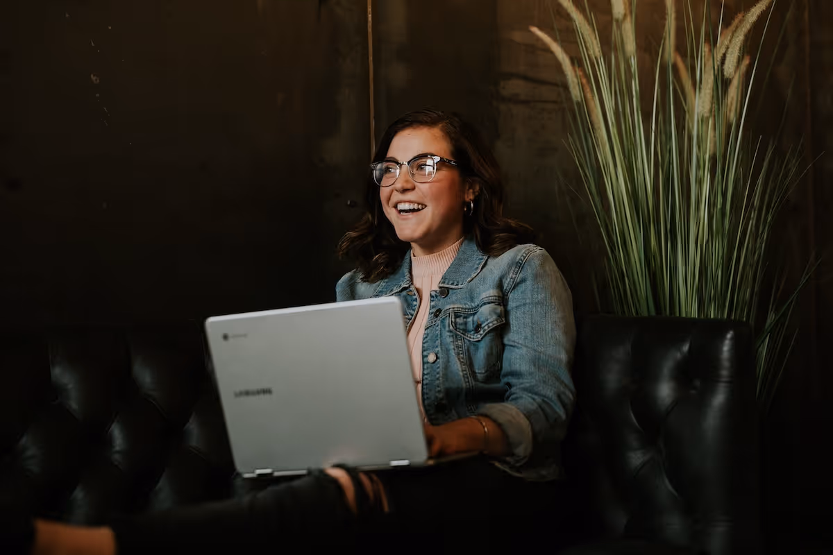 Woman sitting on a couch with a silver laptop