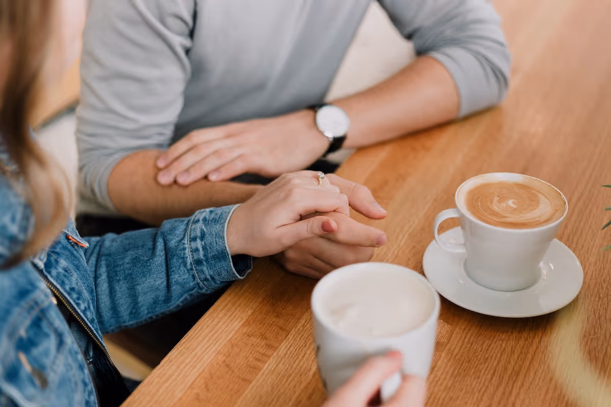 Couple holding hands over coffee