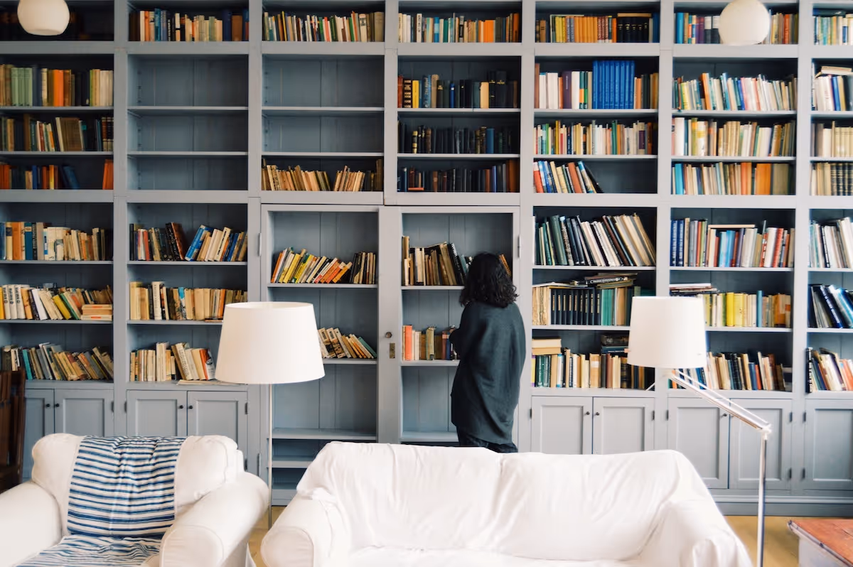 Girl in blue sweater standing in front of book shelf