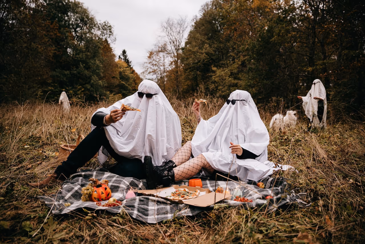 colleges students dressed up as sheet ghosts having a picnic on campus