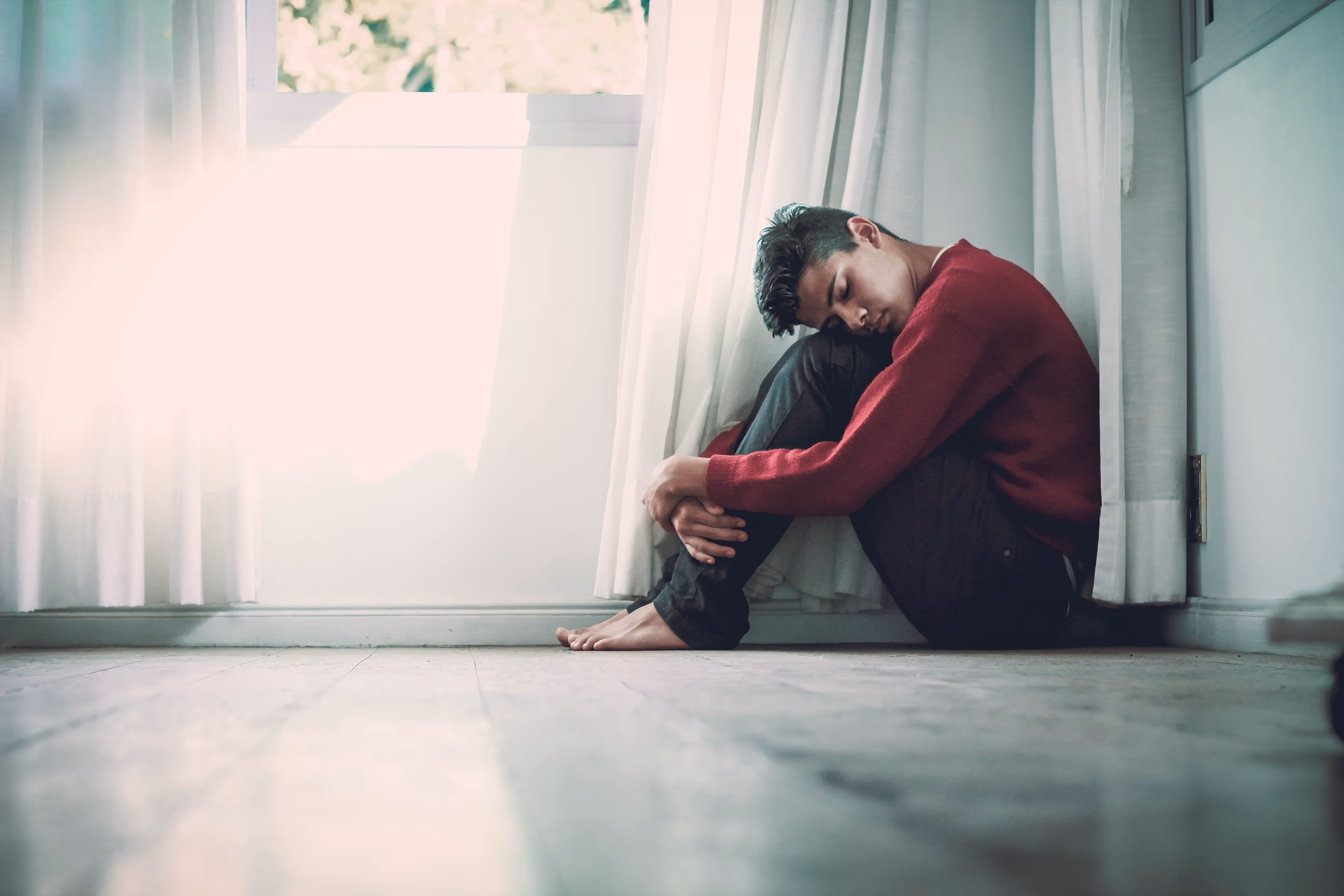 anxious 20something man curled on the floor