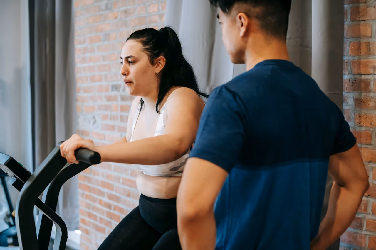 personal trainer encouraging woman losing weight on an elliptical