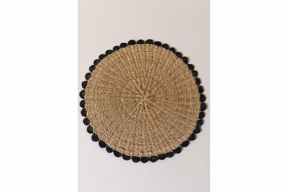 Circular placemat with navy blue border in a scalloped style. 