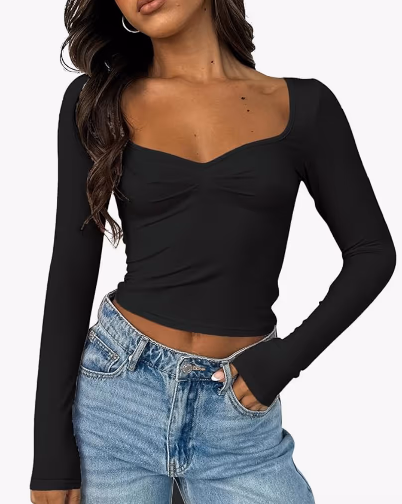 woman wearing a long sleeve black top with a square neck and subtle ruching on the chest