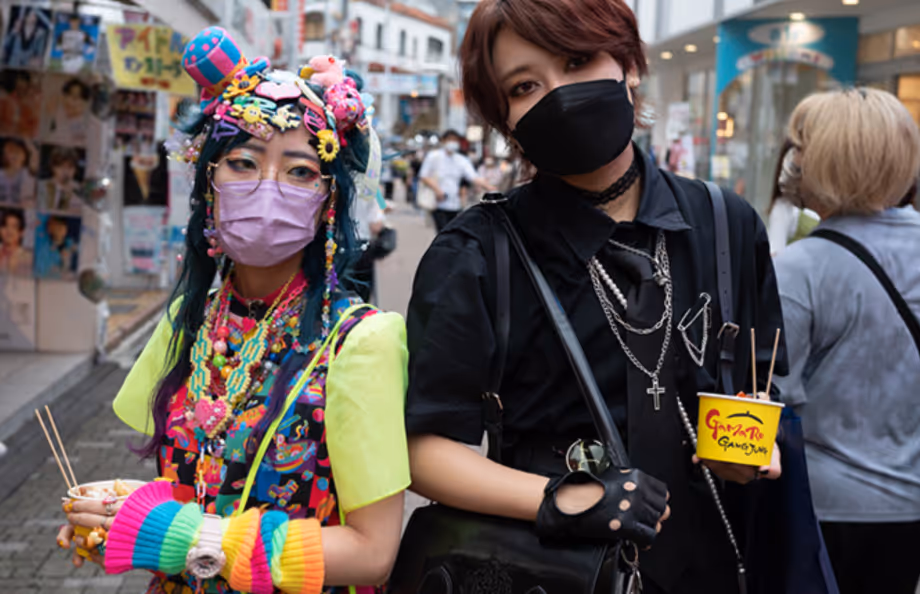 a girl in colorful japanese alternative street fashion and a man wearing all black