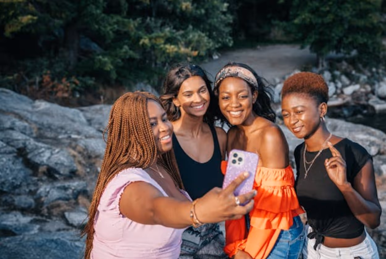 Four women smiling and posing together for a selfie, capturing a joyful moment of friendship and camaraderie.  