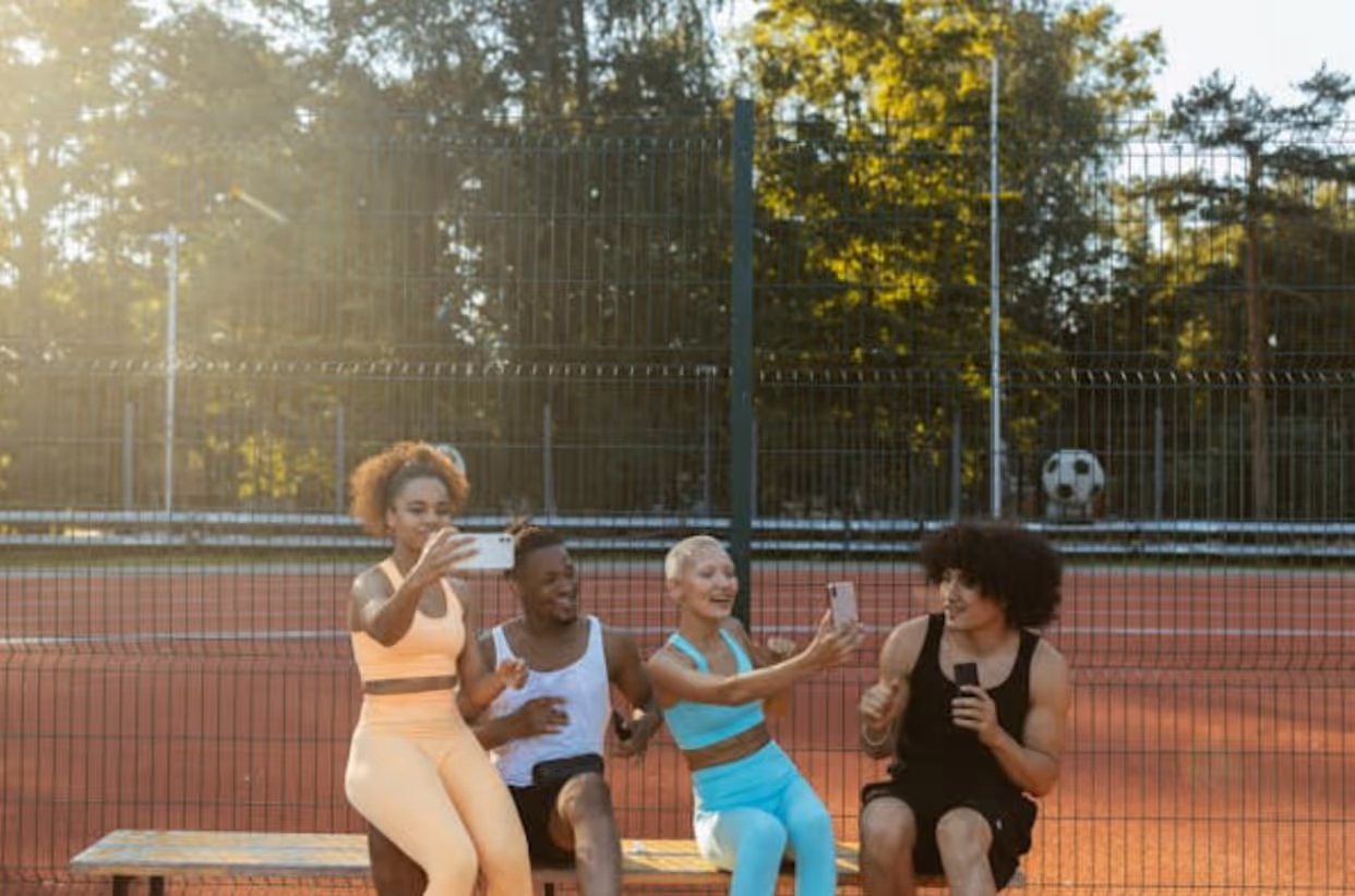 Four individuals seated on a bench, with a soccer ball resting on the ground beside them. 